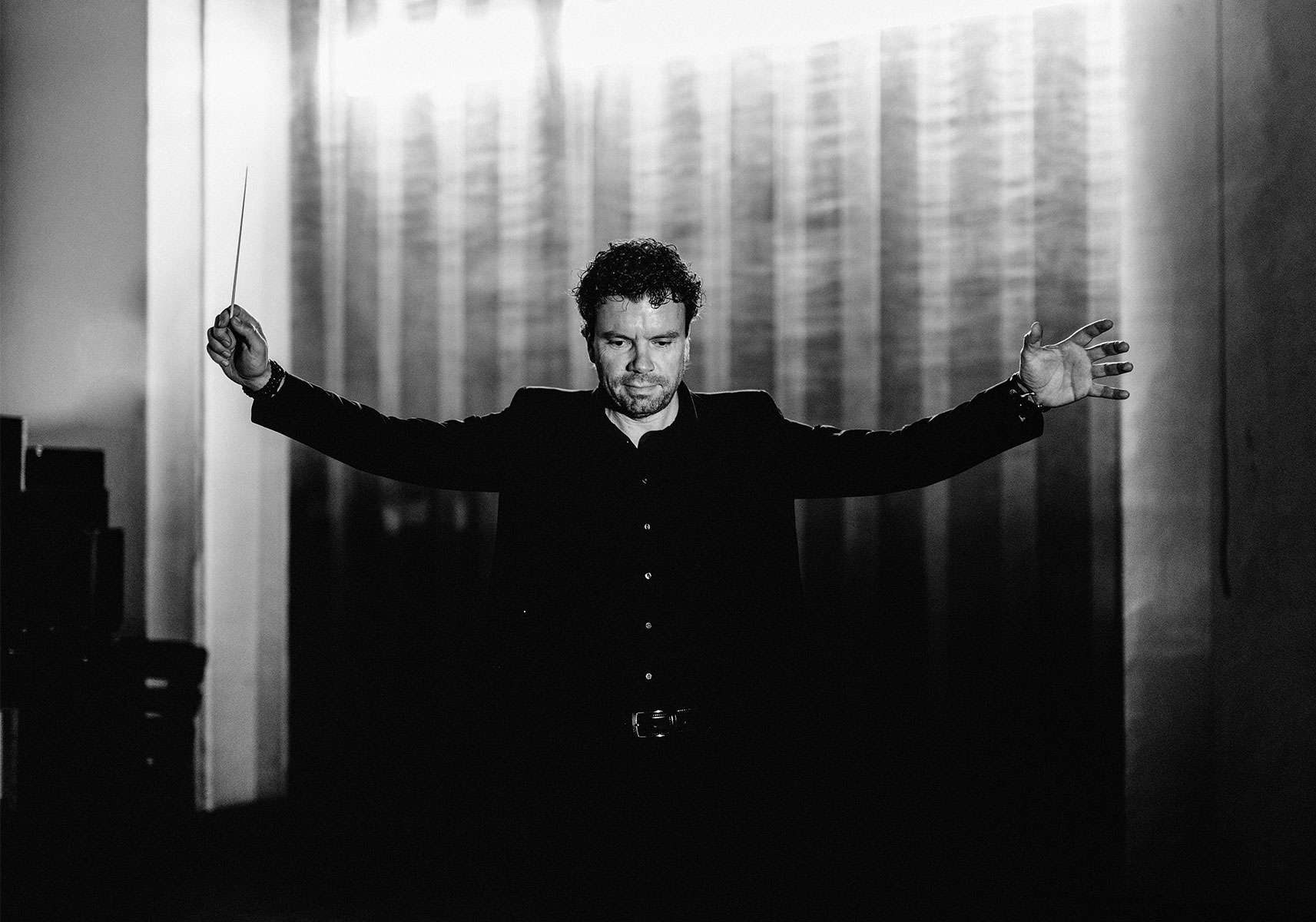 Paul Lorenz conducting, baton raised and arms outstretched